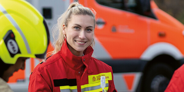 Frau in Rettungsdienstkleidung vor Rettungswagen