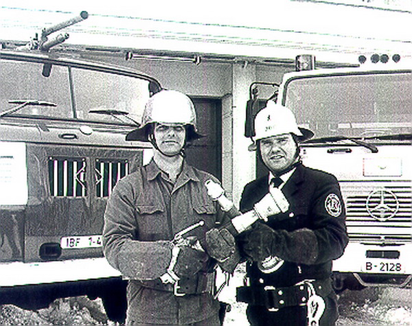 Zwei Feuerwehrleute vor Einsatzfahrzeugen