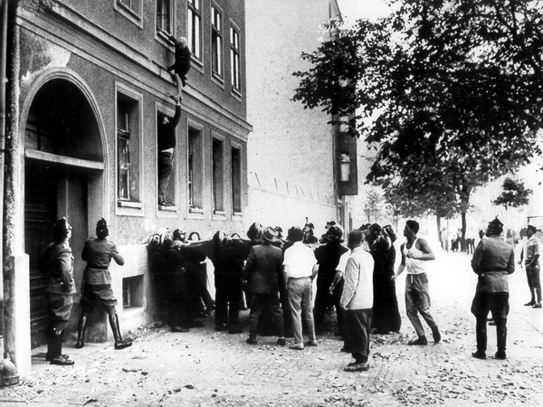 Frau klettert aus dem Fenster, Feuerwehrleute mit Sprungtuch