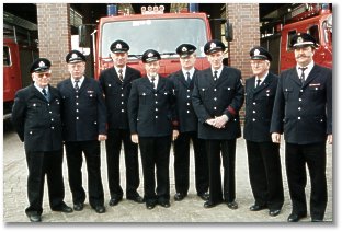 8 Feuerwehrleute vor Wachgebäude