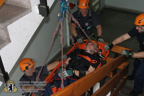 Person in Trage beim seilunterstützten Transport im Treppenhaus