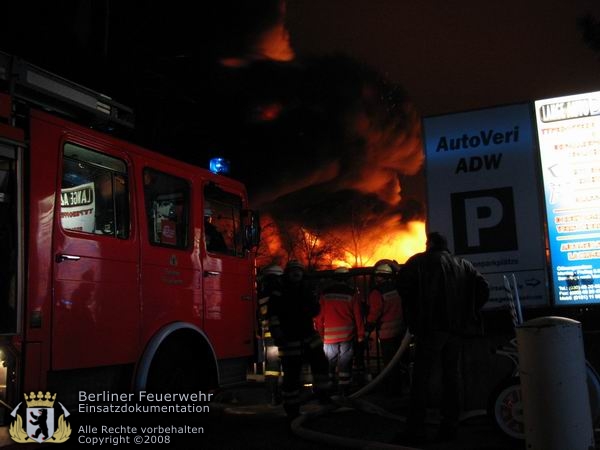 Feuerwehrfahrzeug vor brennender Halle