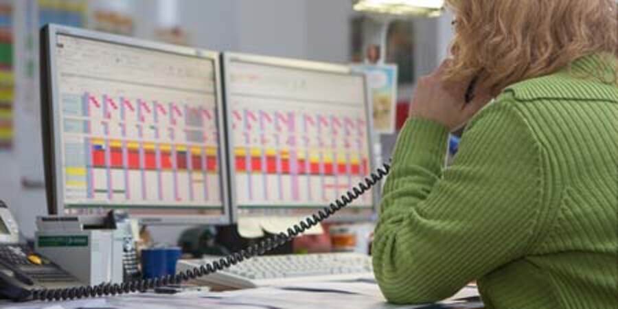Telefonierende Person vor Bildschirmen
