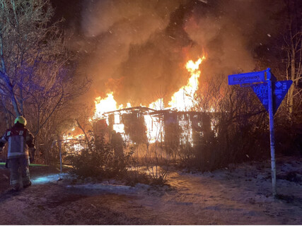 Einsatzkräfte vor der im Vollbrand befindlichen Laube.