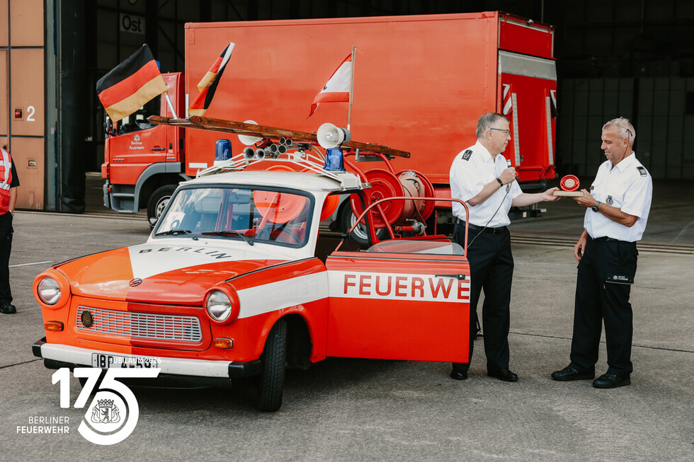 Übergabe einer symbolischen Kupplung durch Landesbranddirektor Prof. Dr. Karsten Homrighausen an Hans‑Jörg Schierz, Mitorganisator des Fahrzeugkorsos.