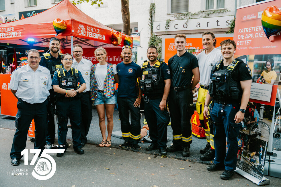 Gruppenfoto der Mitarbeitenden der Berliner Feuerwehr zusammen mit den Einsatzkräften der Polizei Berlin am Informationsstand der Berliner Feuerwehr.