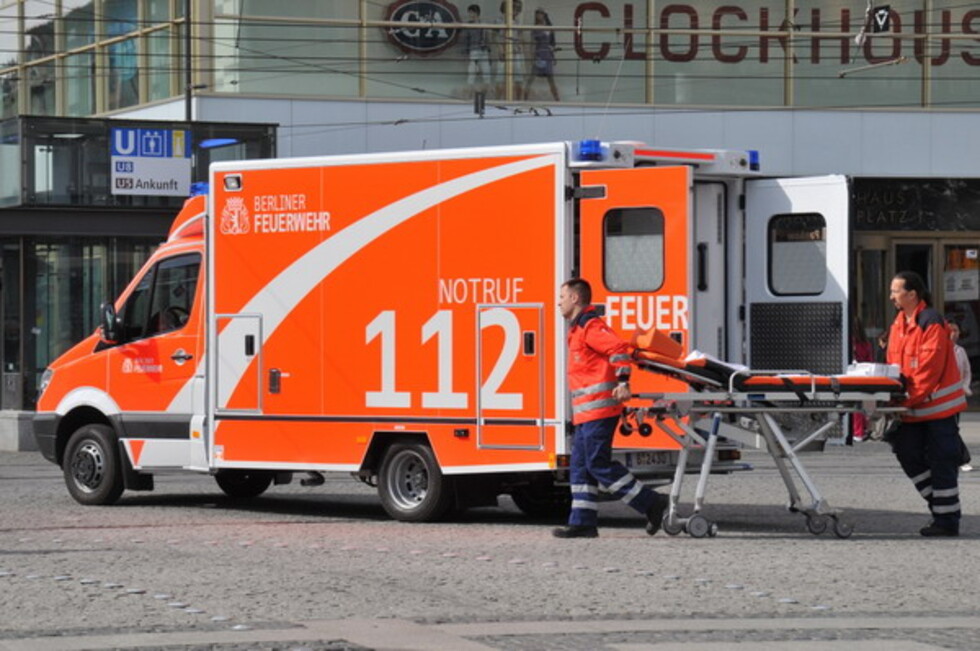 Zwei Einsatzkräfte mit Trage vor einem Rettungswagen