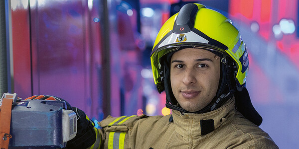Feuerwehrmann in Schutzkleidung mit Helm am Einsatzfahrzeug