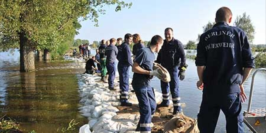 Feuerwehrleute sichern einen Deich bei Hochwasser