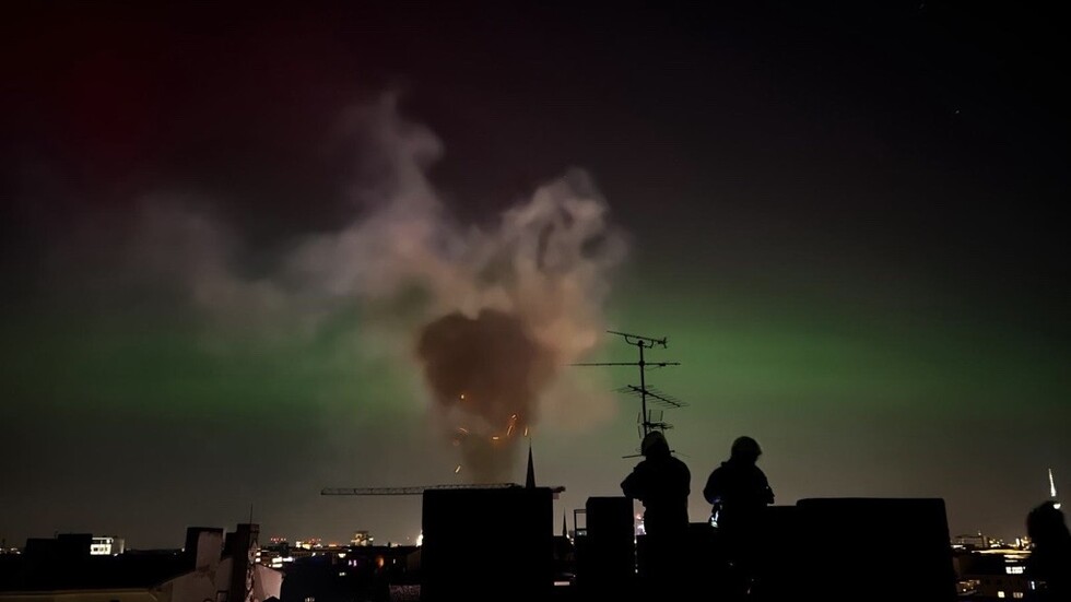 Im Vordergrund: Rauch und Funken aus dem Schornstein; Im Hintergrund: Nordlichter