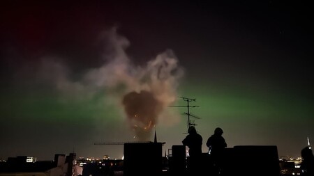 Im Vordergrund: Rauch und Funken aus dem Schornstein; Im Hintergrund: Nordlichter