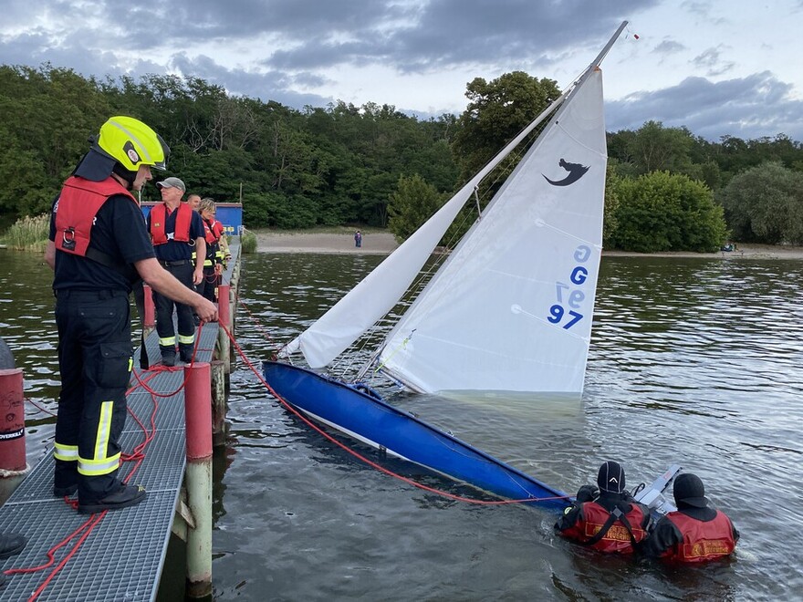 Feuerwehrtaucher bergen Gegenstände vom gekenterten Segelboot