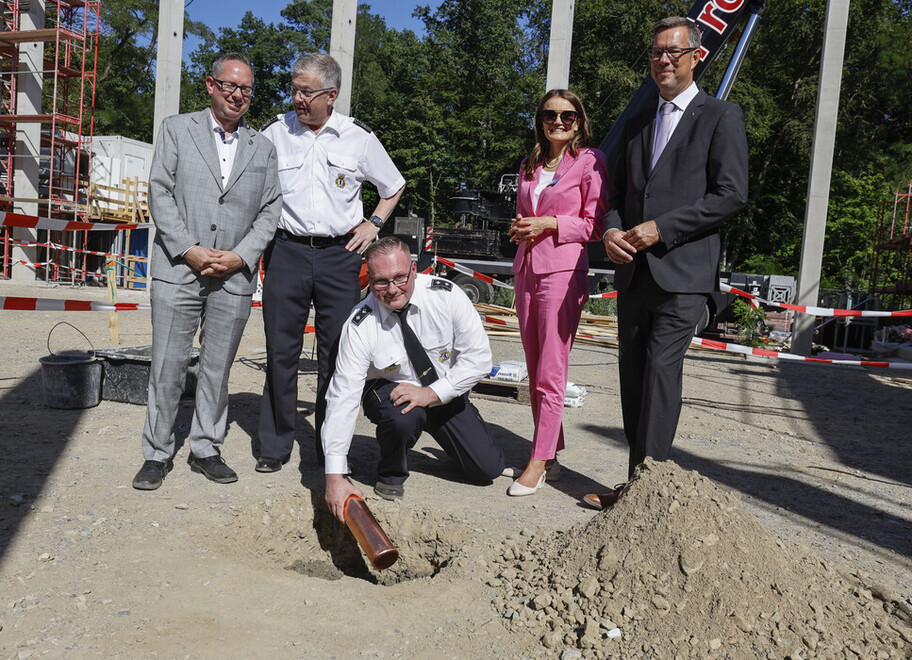 Der Wehrleiter der FF Wilhelmshagen legt den Grundstein in eine Grube auf der Baustelle.