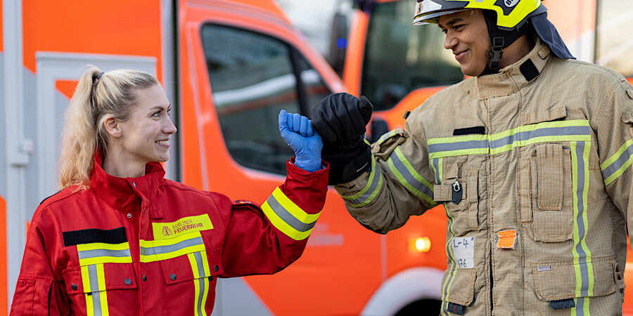 Notfallsanitäterin und Feuerwehrmann vor Rettungswagen