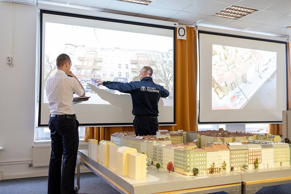 Zwei Personen betrachten eine Videoleinwand
