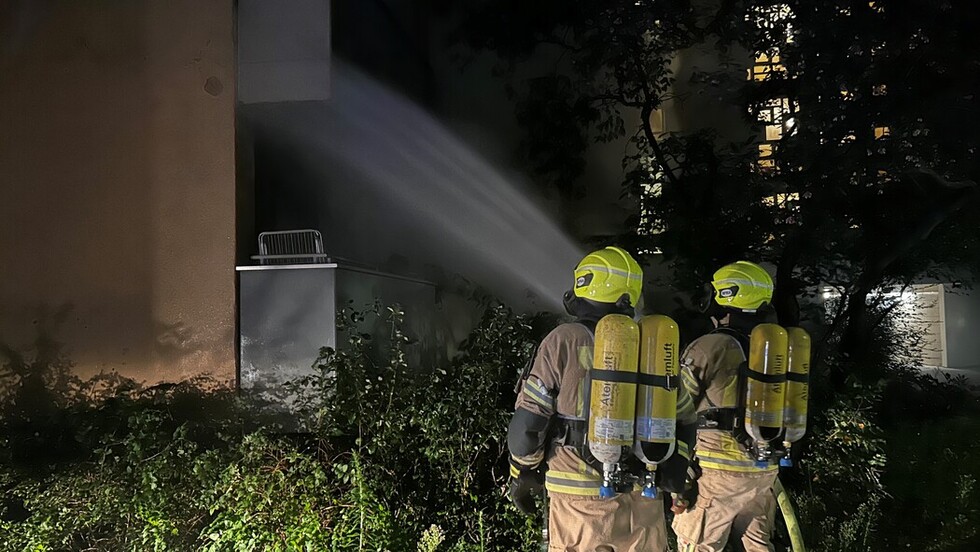 Einsatzkräfte mit Atemschutzgeräten löschen den Brand von außen