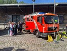 Feuerwehrmann erklärt Besuchergruppe die Ausrüstung eines Löschfahrzeugs