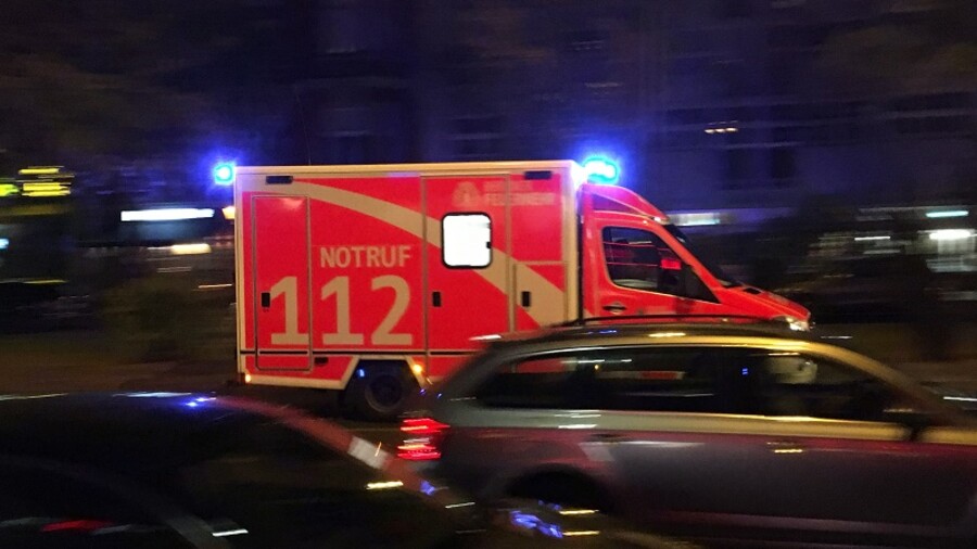 Ein Rettungswagen mit Blaulicht im nächtlichen Stadtverkehr