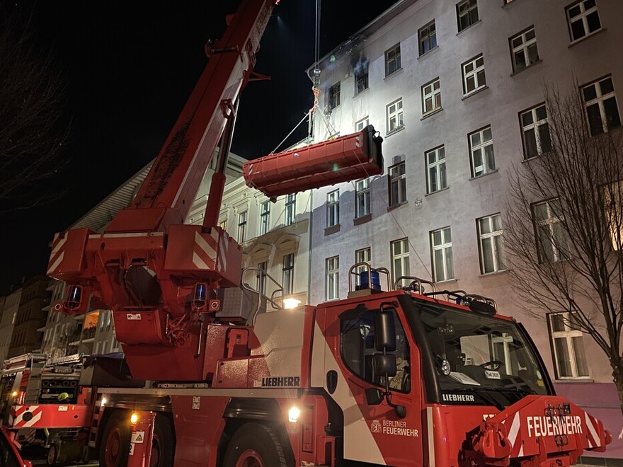 Mulde wird mittels Feuerwehrkran zur Brandwohnung gebracht