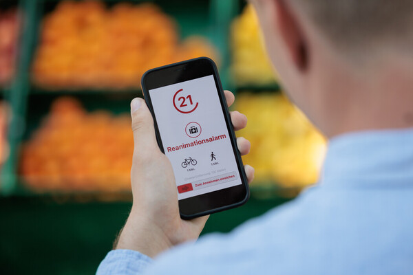 Person im Supermarkt blickt auf Smartphone