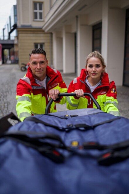 Mitarbeitende schieben in neuer Rettungsdienstkleidung Trage in den RTW.