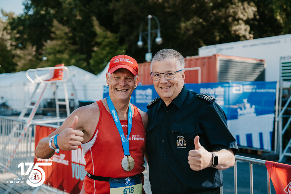 Landesbranddirektor Prof. Dr. Karsten Homrighausen überreicht einem Angehörigen der Berliner Feuerwehr nach dem Zieleinlauf die Finisher-Medaille.