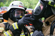 Zwei Feuerwehrleute mit Helm und Atemschutzmaske