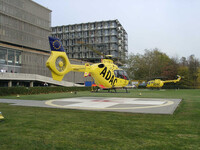 Hubschrauber auf Landeplatz vor Klinikgebäude