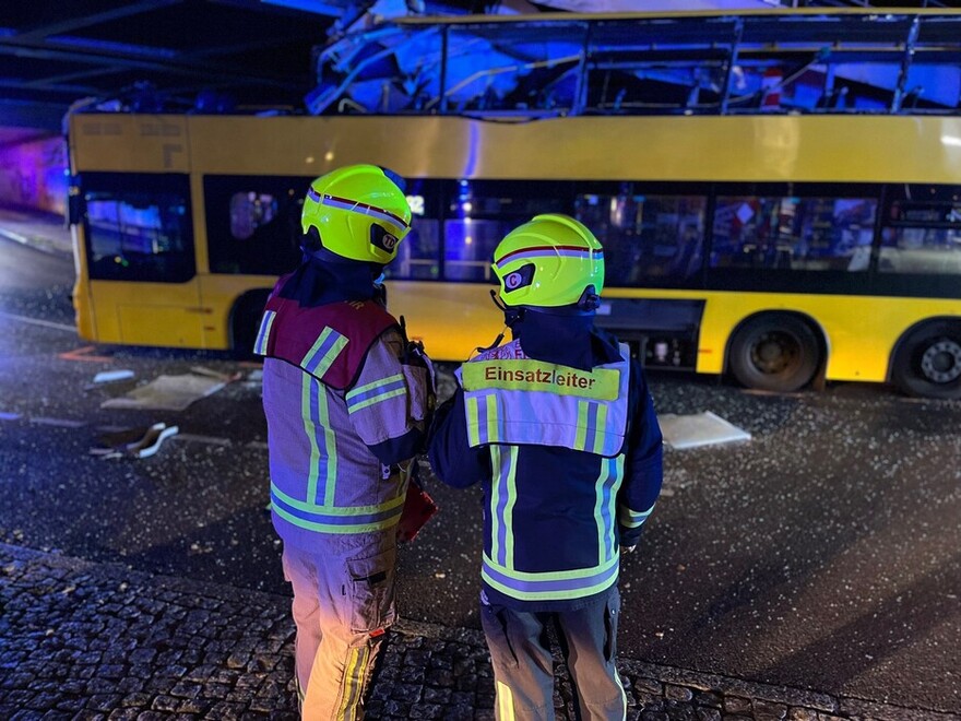 Einsatzleiter und Staffelführer des Technischen Dienstes stehen vor dem festgefahrenen Bus und beraten weiteres Vorgehen