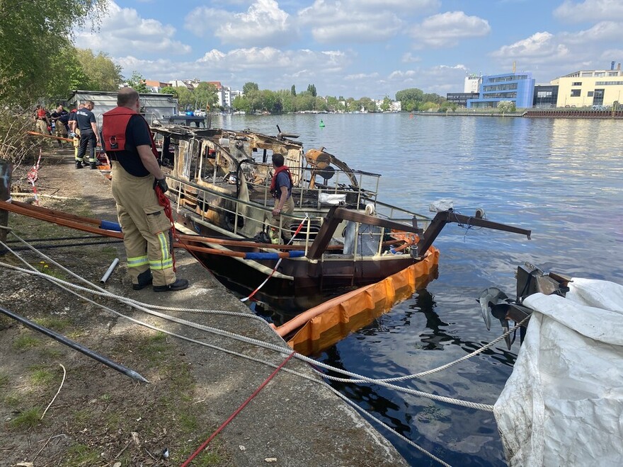 Gesetzte Ölsperre um das ausgebrannte Bootswrack