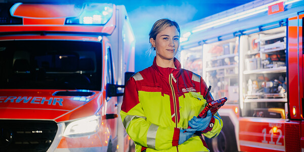 Notfallsanitäterin steht vor Einsatzfahrzeug