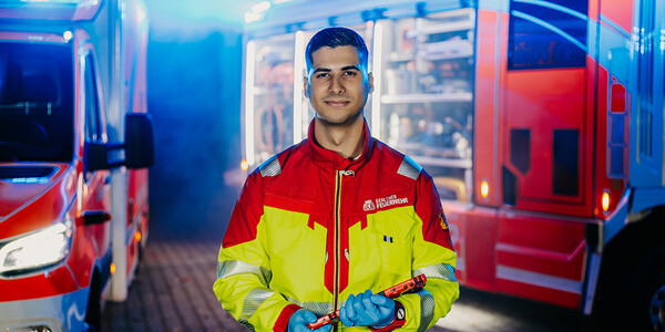 Notfallsanitäter steht vor Einsatzfahrzeugen