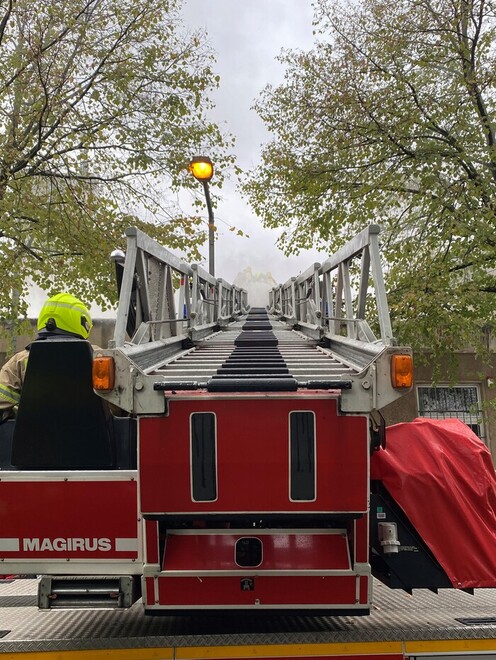 Blick entlang der ausgefahrenen Drehleiter zum brennenden Dach hin.