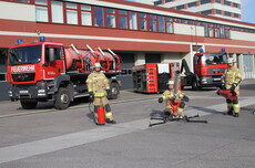 Feuerwehrleute mit Ausrüstung vor Fahrzeugen