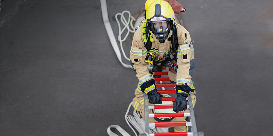 Person in Schutzkleidung auf Drehleiter