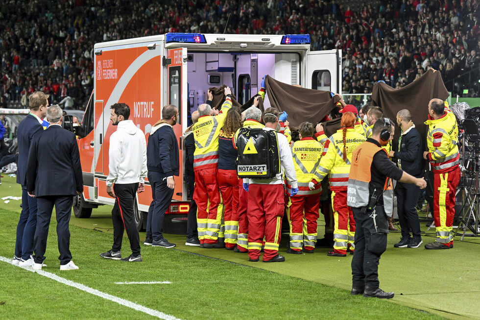 Behandlung des Patienten am Rande des Spielfeldes durch den Sanitätsdienst sowie das Rettungsdienstpersonal.