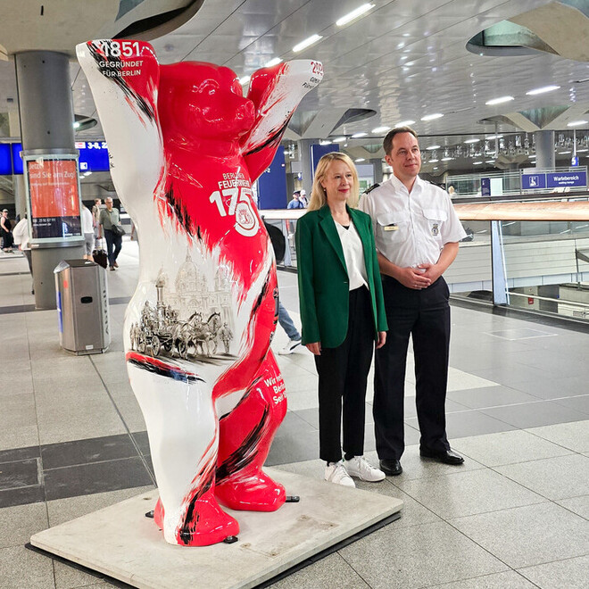Der Ständige Vertreter des Landesbranddirektors Per Kleist mit Monika Jung, Leiterin des Bahnhofsmanagements der Berliner Fernbahnhöfe bei der Deutschen Bahn neben dem neuen Buddy Bären.