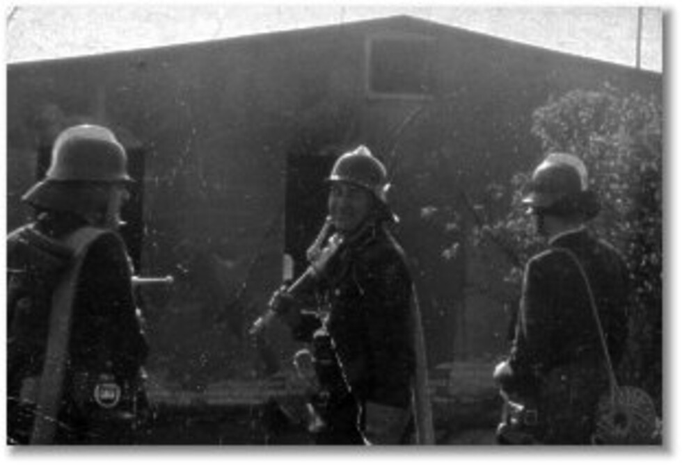 Drei Feuerwehrleute vor Lagerhalle