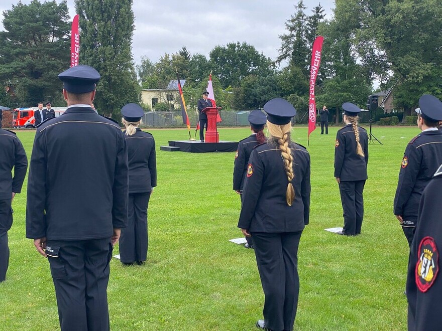 Kameradinnen und Kameraden der Freiwilligen Feuerwehr in Formation horchen der Rede von Herrn Göwecke