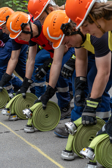 Mitglieder der Jugendfeuerwehr beim einrollen der Feuerwehrschläuche