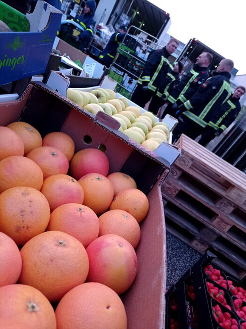 Ehrenamtliche Helfer laden Obst und Gemüse auf Lkw.