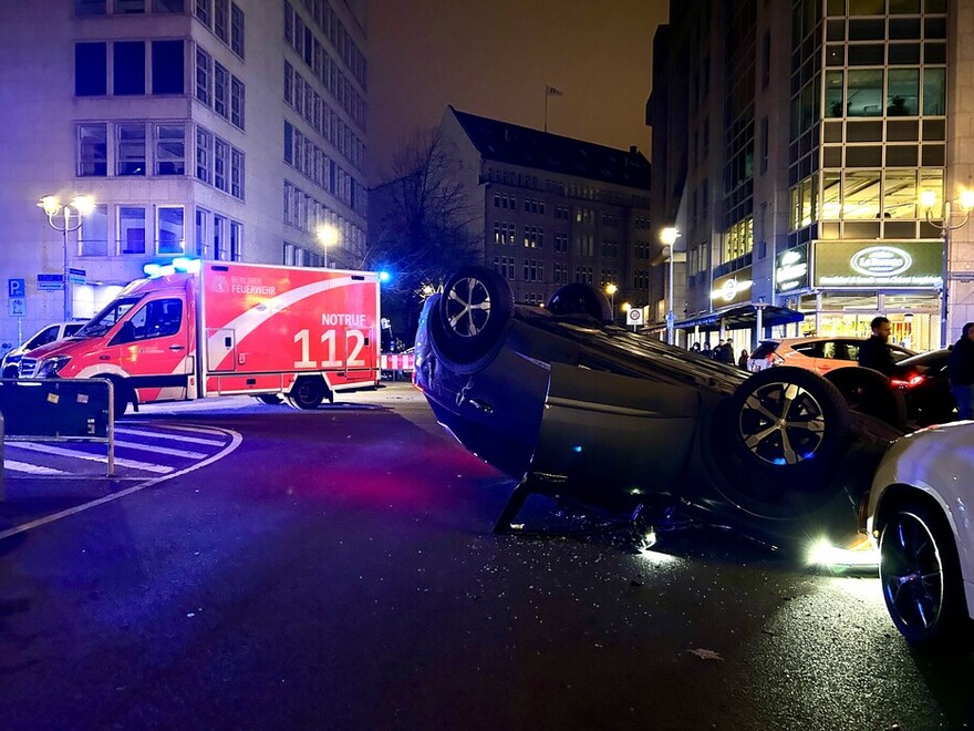 Rettungswagen an der Einsatzstelle mit einem überschlagenen PKW