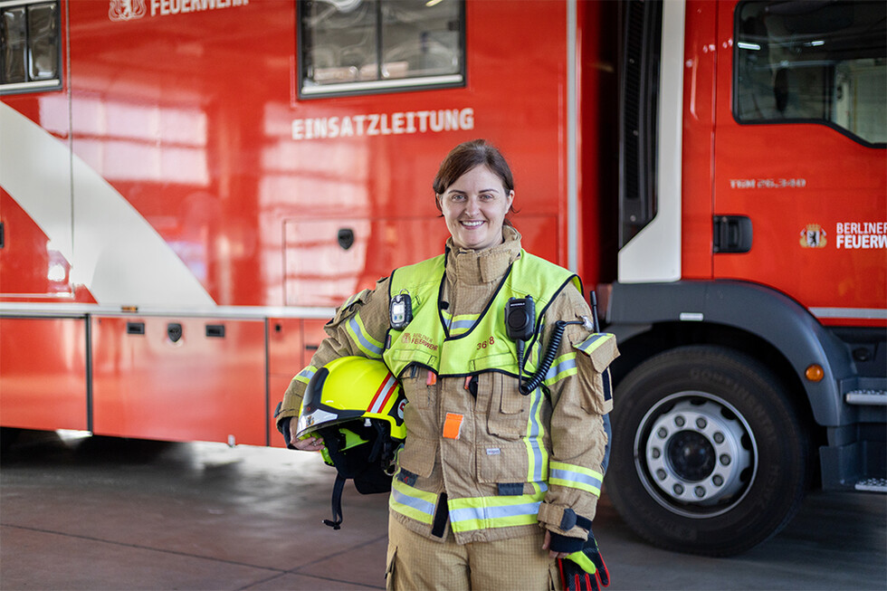 Frau in Feuerwehrschutzkleidung vor Einsatzfahrzeug