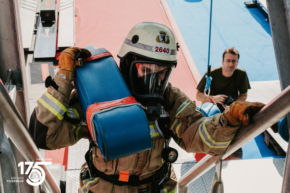 Wettkampfteilnehmerin beim Treppenlauf mit einem 19 Kilogramm schweres Schlauchpaket.