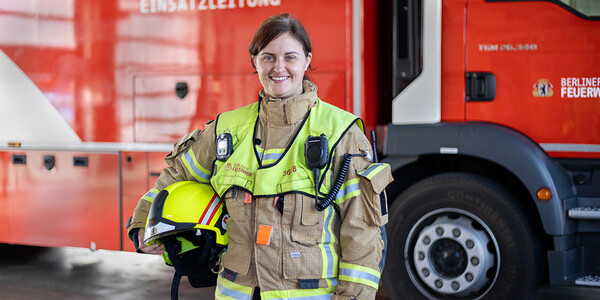 Frau in Schuztkleidung vor Einsatzfahrzeug