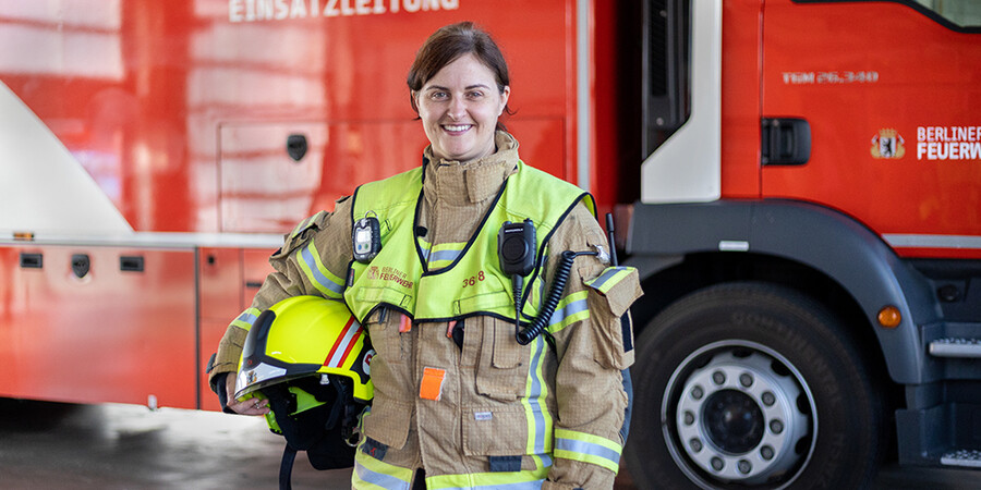 Frau in Schuztkleidung vor Einsatzfahrzeug