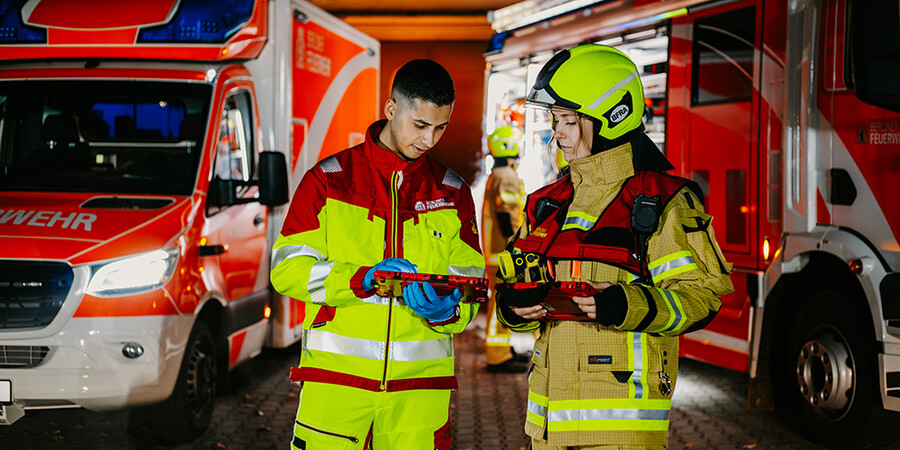 Zwei Feuerwehrleute stehen vor Einsatzfahrzeugen