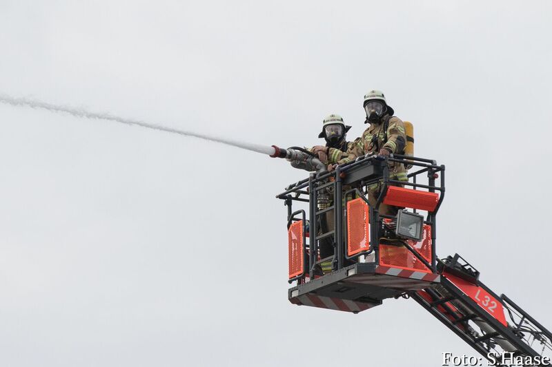 Zwei Einsatzkräfte im Korb einer Drehleiter bei der Brandbekämpfung