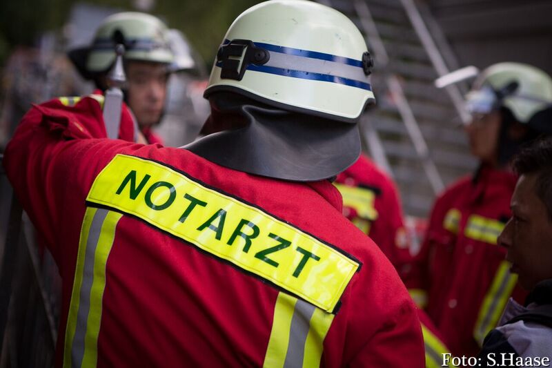 Einsatzkraft in Rettungsdienstkleidung mit Helm und Rückenschild Notarzt