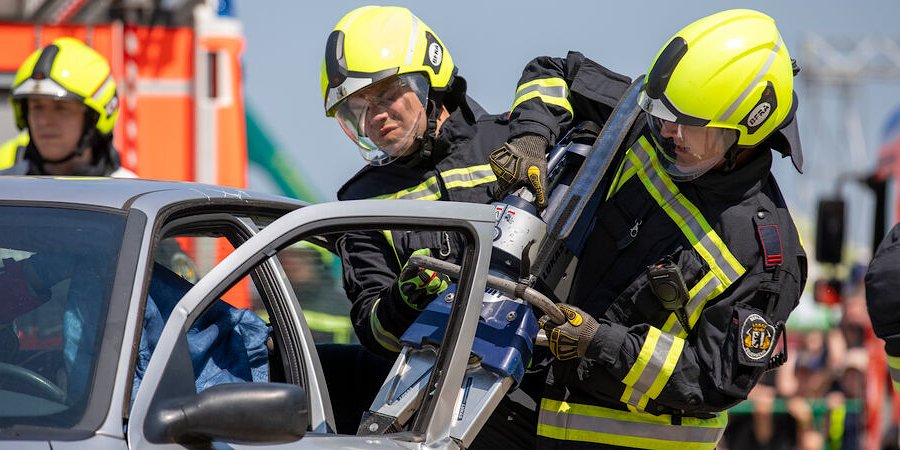Zwei Feuerwehrleute öffnen eine Fahrzeugtür mit Spreizgerät 